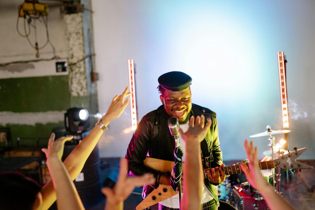 Musician performing energetically on stage with a guitar, engaging the lively audience.